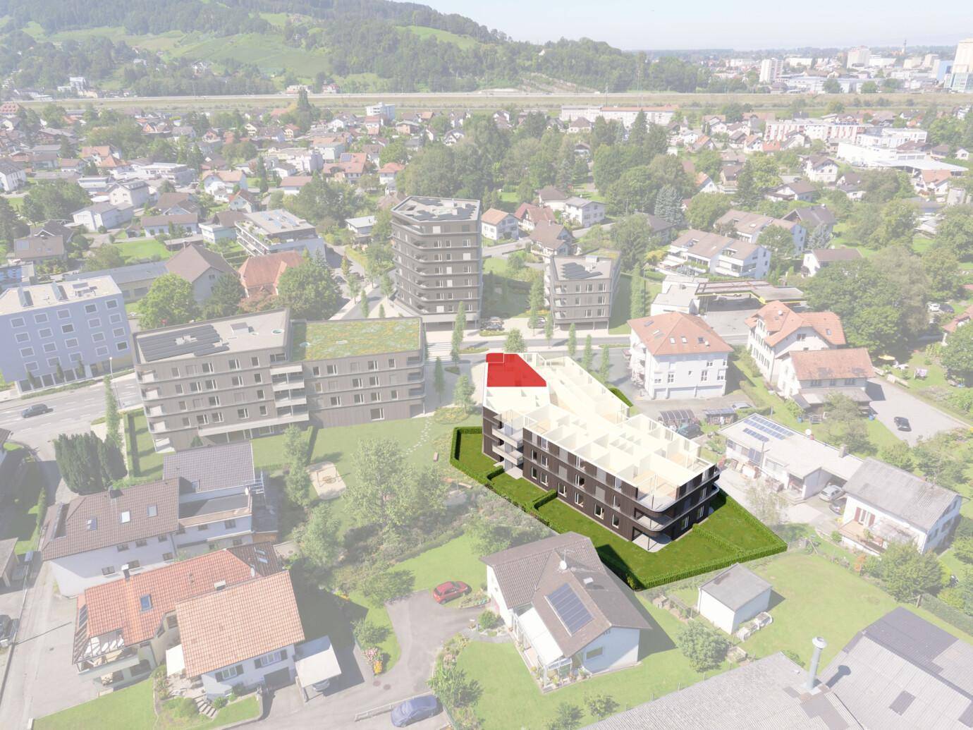 Luftaufnahme eines modernen Neubaus in städtischer Umgebung mit viel Grün und Bergblick.