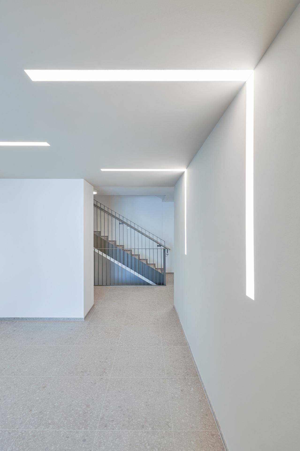 Moderner Flurbereich mit minimalistischer Beleuchtung und Zugang zum Treppenhaus.