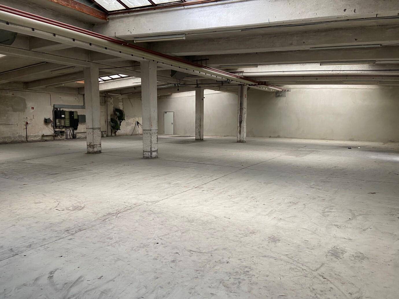 Weitläufiger, unmöblierter Industriebereich mit robustem Betonboden und sichtbaren Deckenstrukturen.