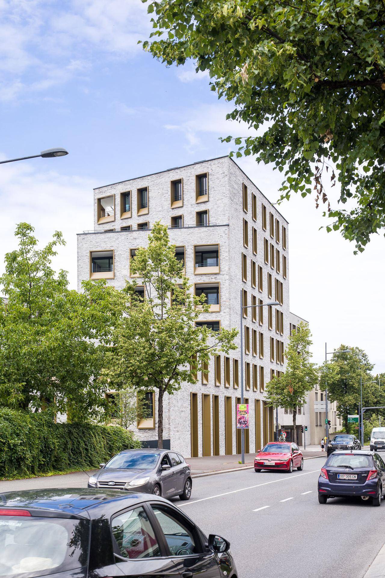 Ansicht des modernen Wohngebäudes von der Straße mit umliegenden Bäumen.