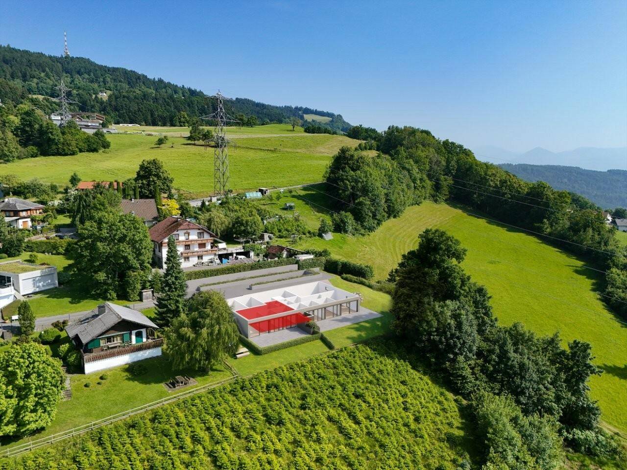 Luftaufnahme eines modernen Gebäudekomplexes eingebettet in eine grüne Hügellandschaft.