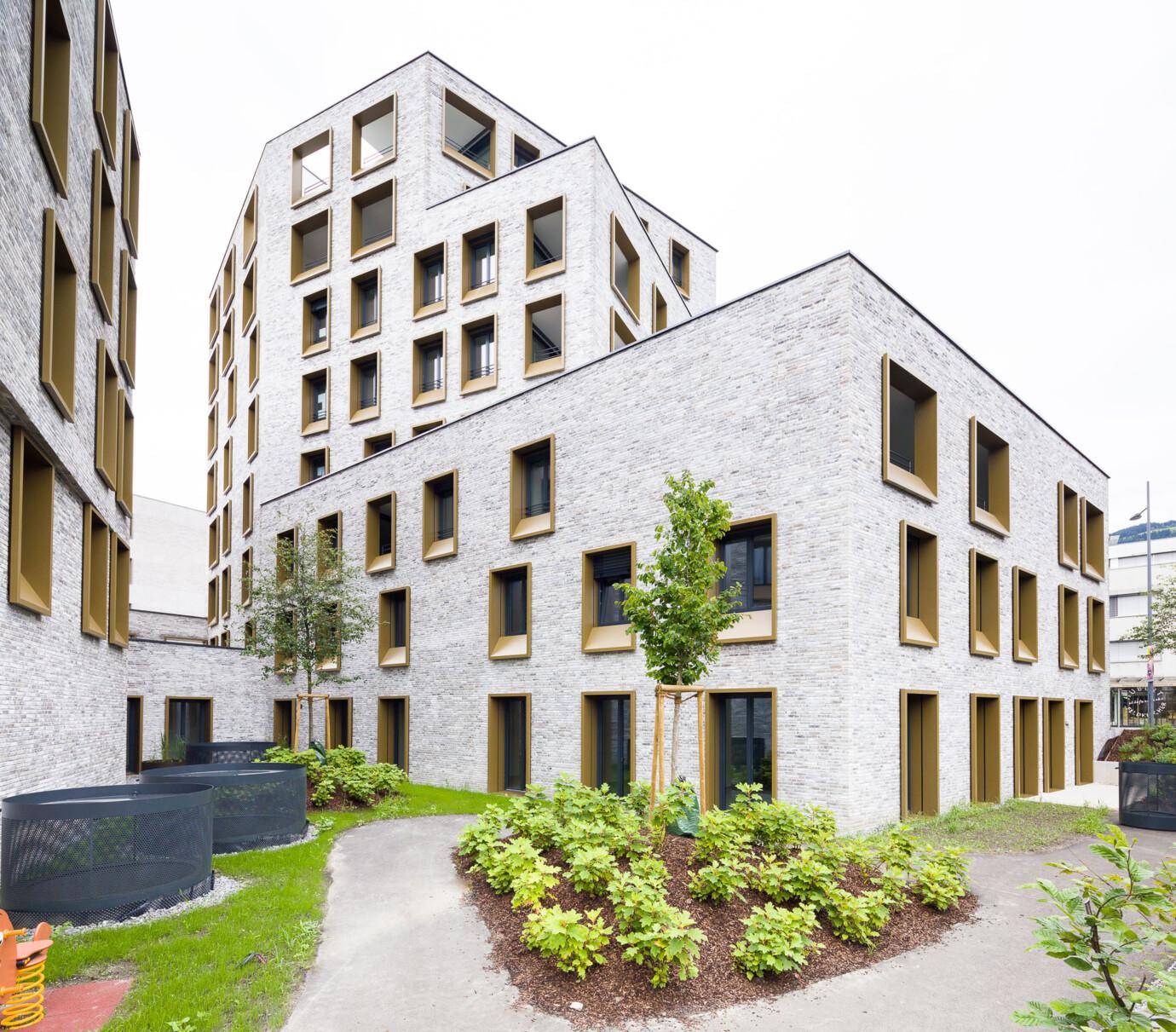 Modernes Gebäude mit heller Fassade und einem schön angelegten grünen Innenhof.