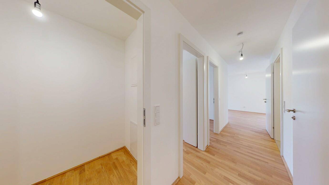 Heller Flur mit Holzboden und mehreren Türen zu den angrenzenden Räumen.