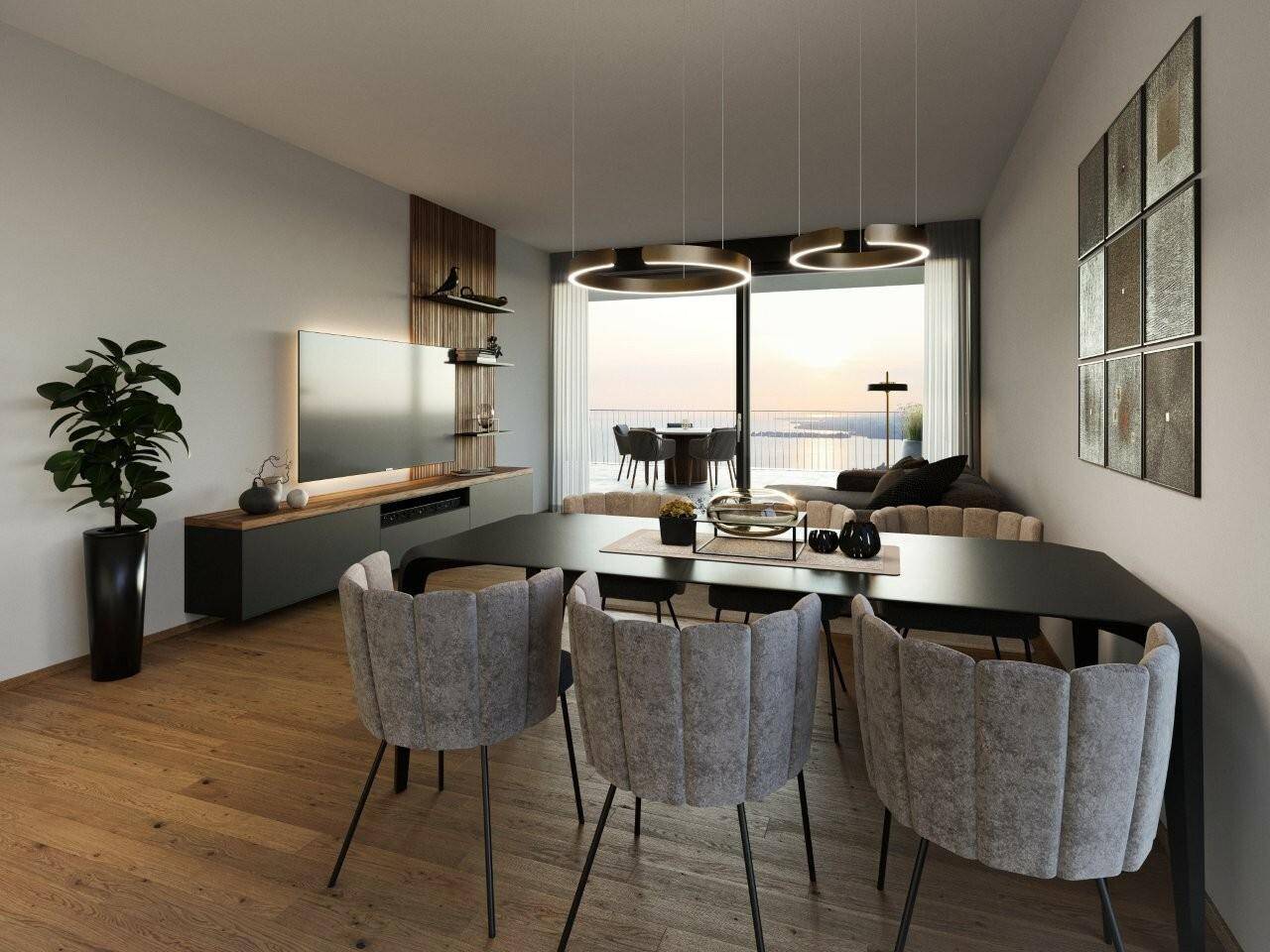 Modernes Wohnzimmer mit Esstisch, grauen Stühlen, Fernseher, Pflanzen und Balkon mit Seeblick bei Sonnenuntergang in der Wohnanlage Pfänderhöhe Lochau.