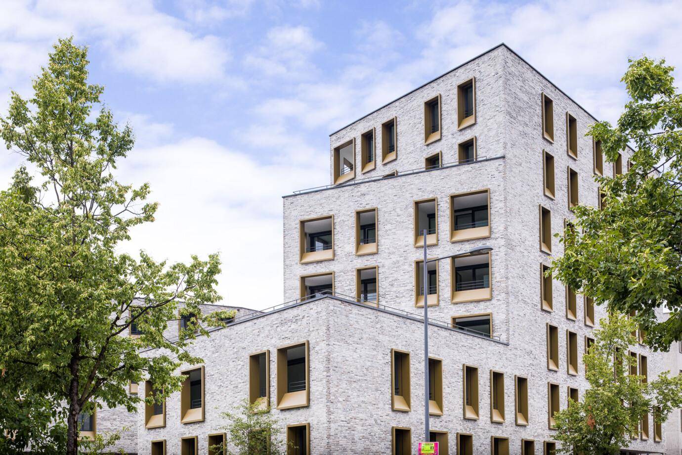 Moderne Architektur des Gebäudes mit heller Ziegelfassade und markanten Fenstern.