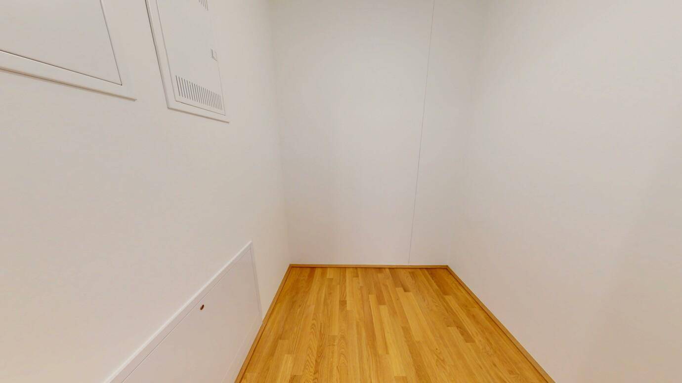 Kleiner Abstellraum mit Holzboden und weißen Wänden, ideal für Lagerung.