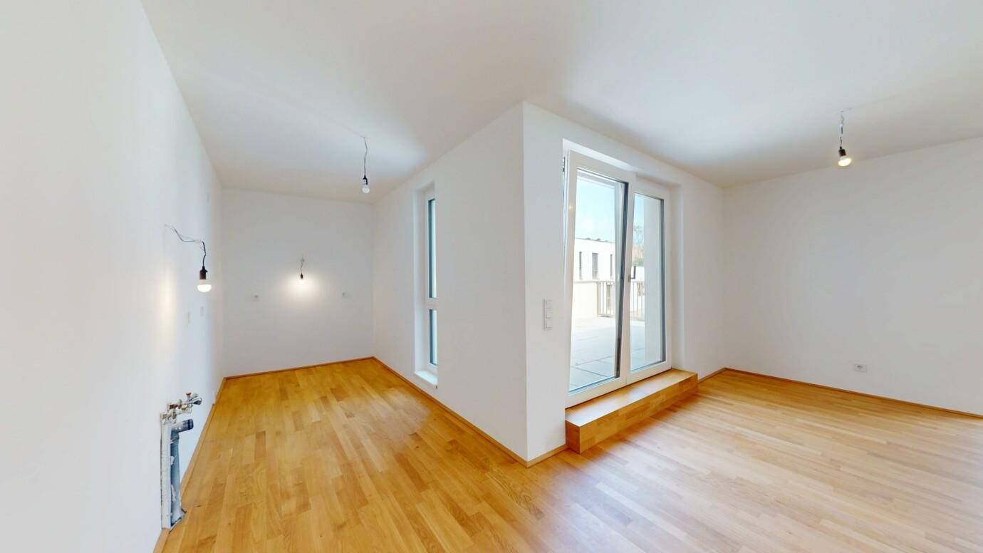 Heller Raum mit Holzboden und breiten Fenstern, bereit für individuelle Gestaltung.