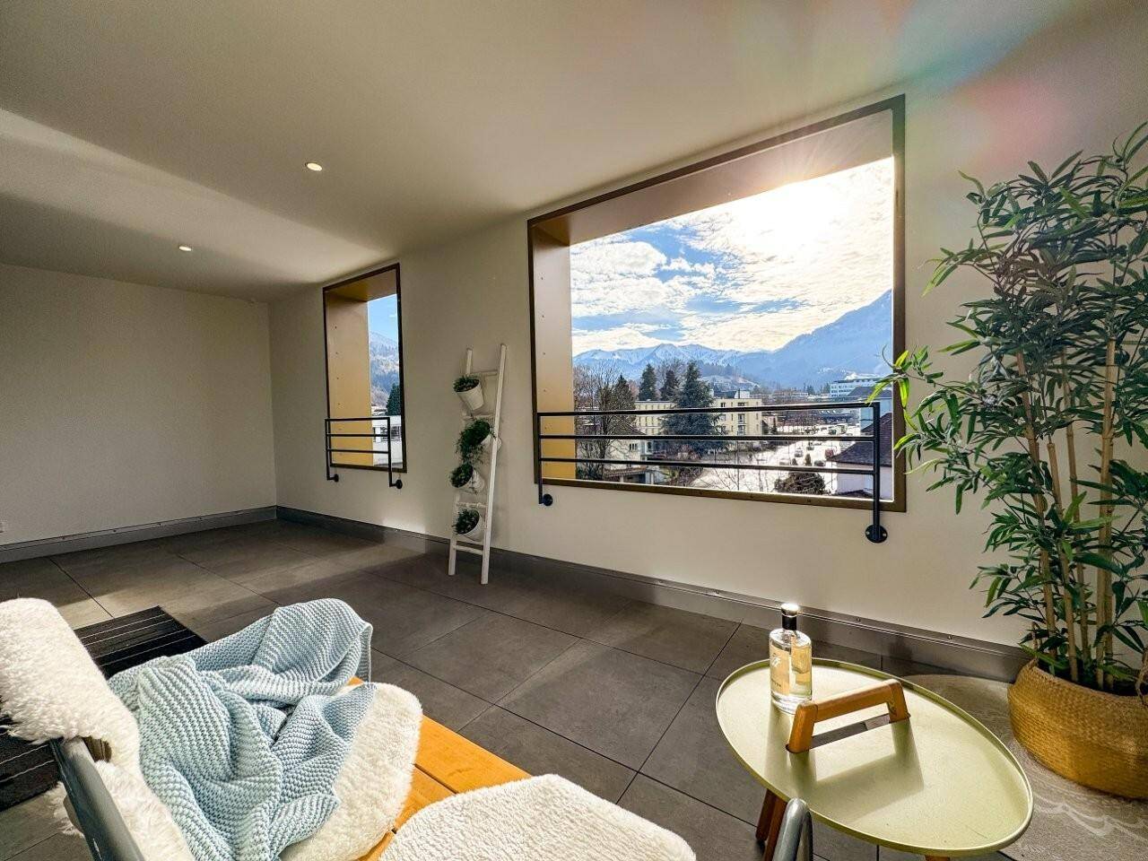 Wohnbereich mit großen Fenstern, Fliesenboden und weitem Blick auf die Berge.