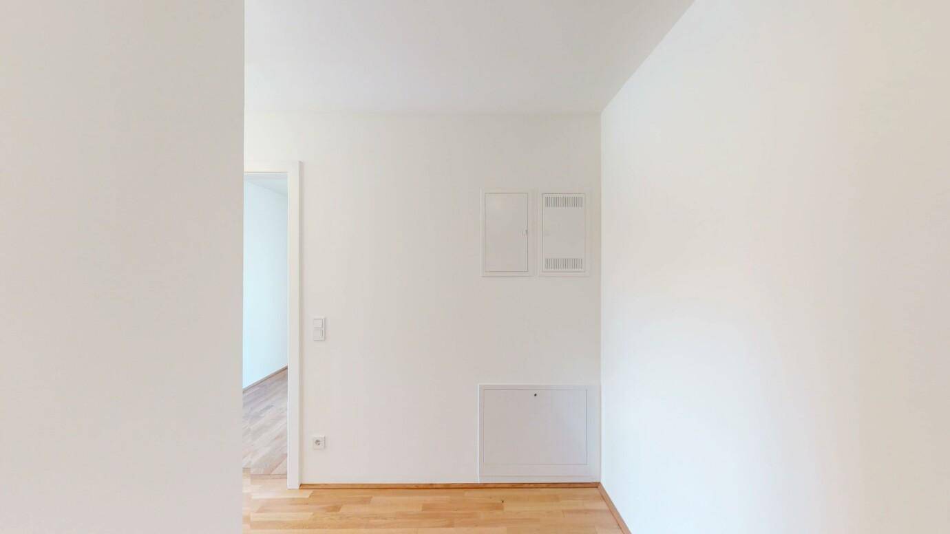 Innenraum mit weißen Wänden und Holzboden, möglicherweise ein Flurbereich.