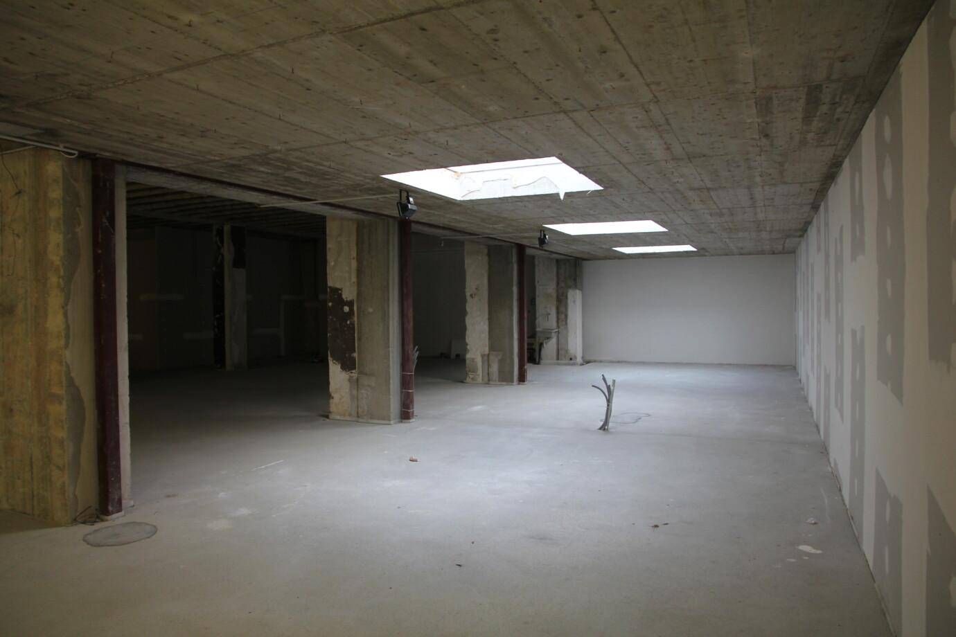 Weitläufiger, unfertiger Innenraum mit Betonstützen und Oberlichtern, bereit für den Ausbau.