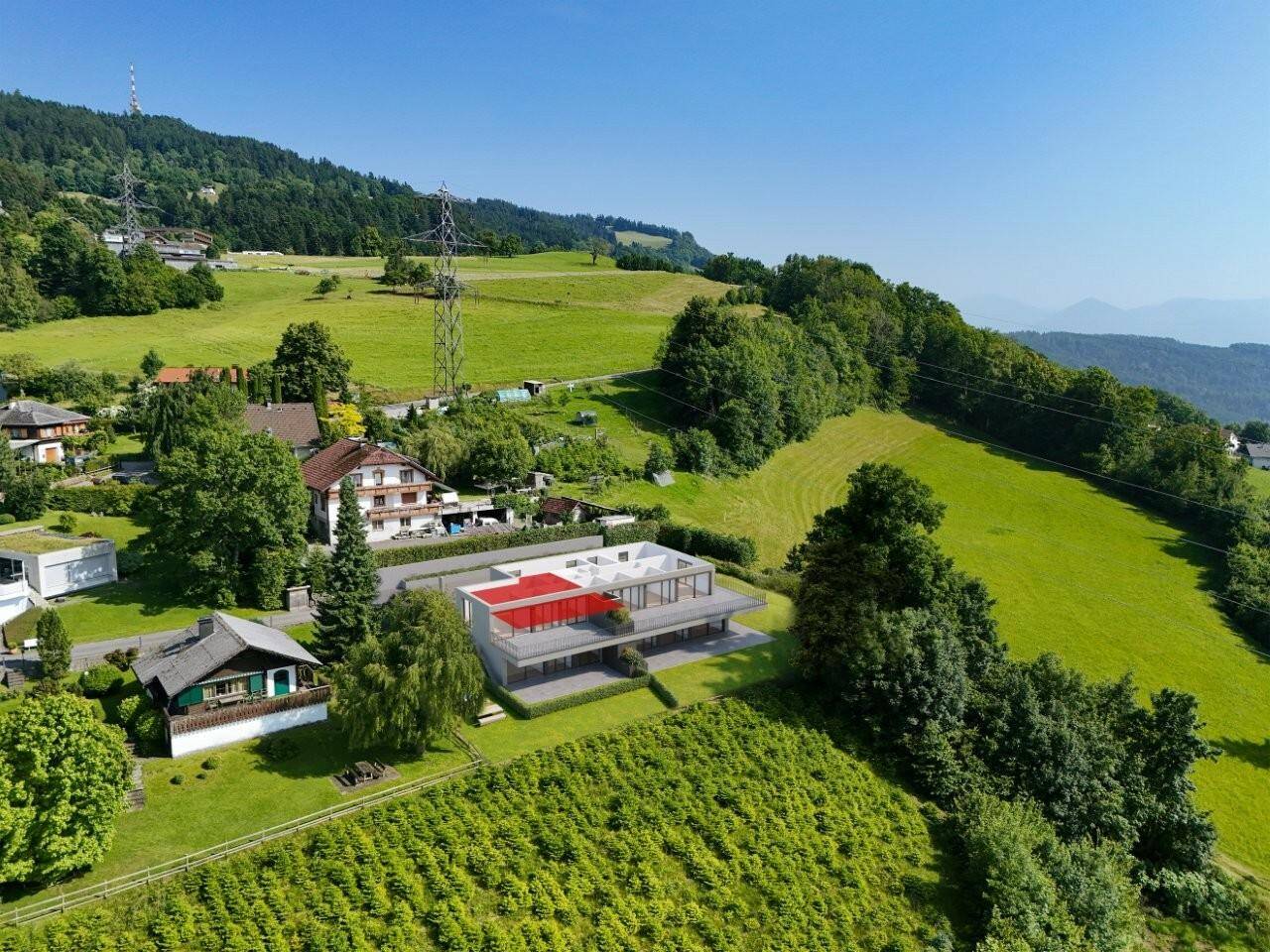 Luftaufnahme eines modernen Neubaus in grüner Hügellandschaft mit Fernblick auf den See.