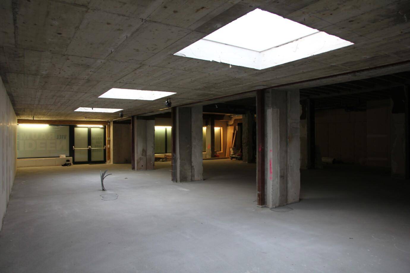 Großer, unfertiger Gewerberaum mit Betonwänden, Betondecke und Oberlichtern für natürliches Licht.