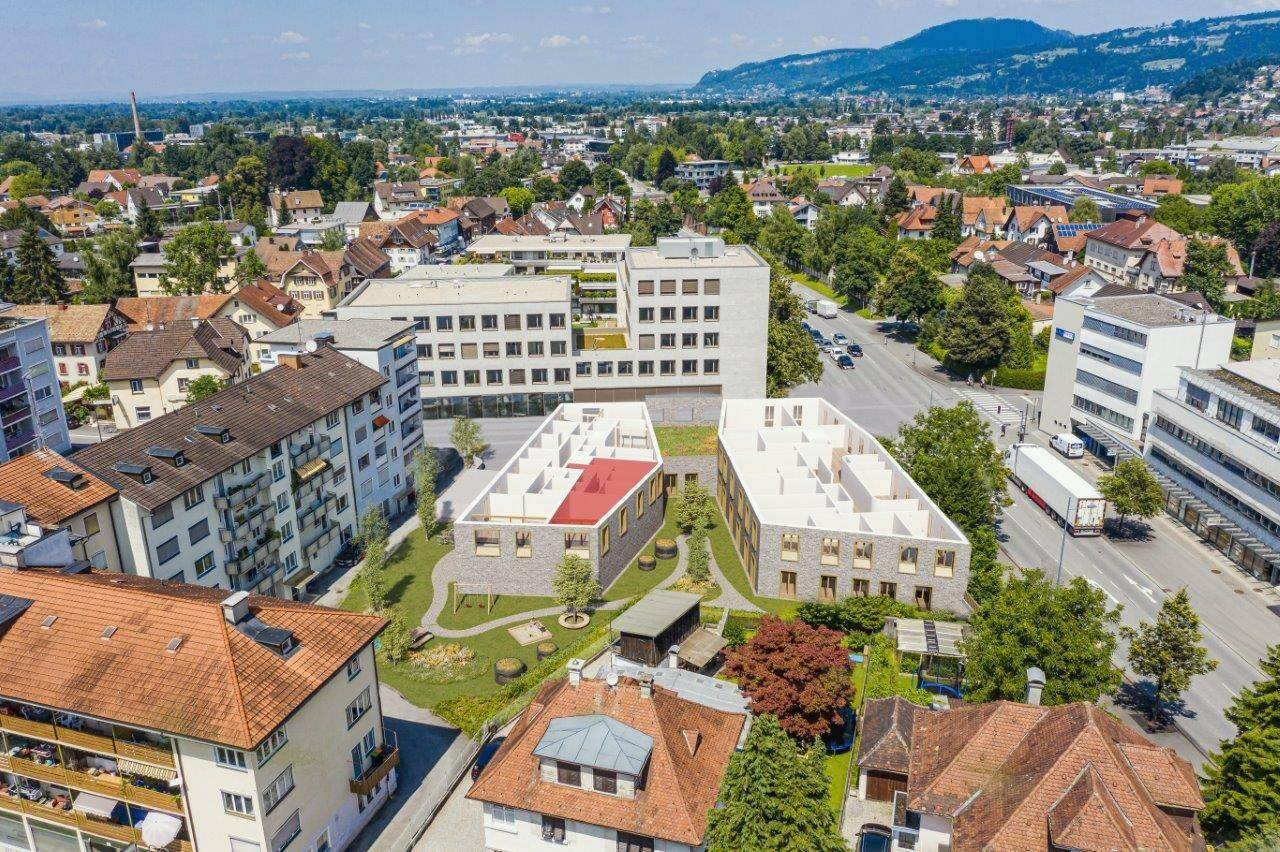 Luftaufnahme eines Neubauprojekts in städtischer Umgebung mit umliegender Bebauung und Grünflächen.