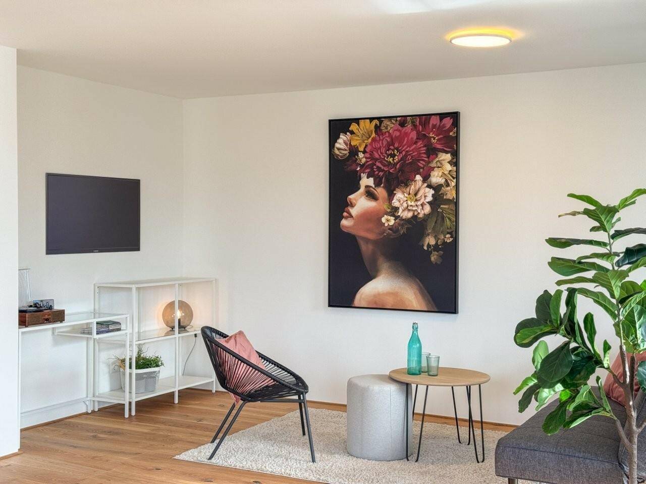 Stilvoller Wohnbereich mit Holzboden, bequemer Couch und einem auffälligen Kunstwerk an der Wand.