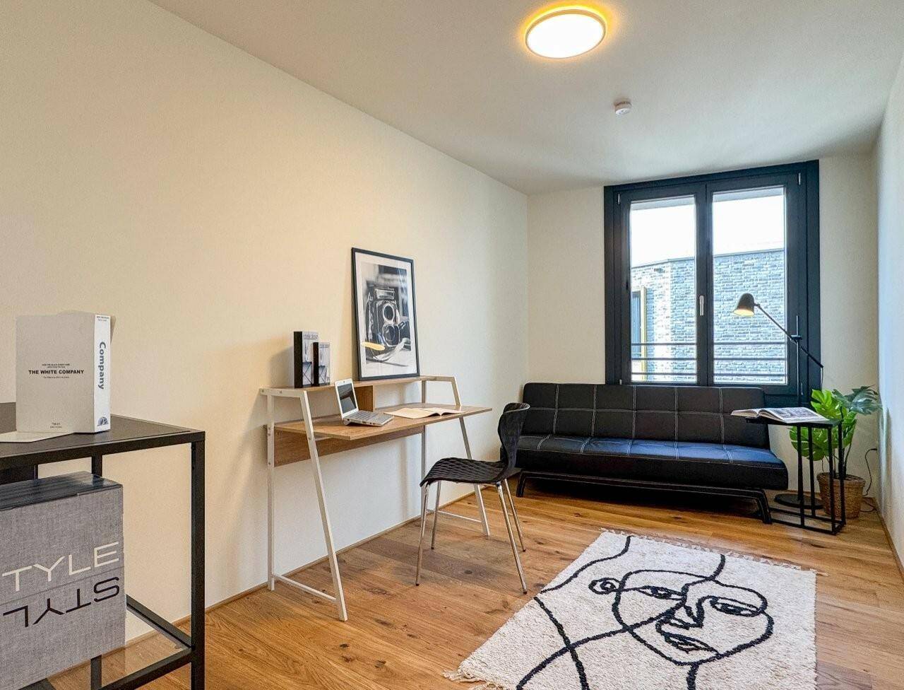 Funktionales Arbeitszimmer mit Holzboden, minimalistischer Einrichtung und Tageslicht.