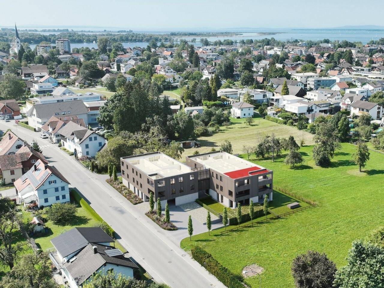 Luftaufnahme der modernen Wohngebäude in einer grünen Umgebung mit Blick auf den See.