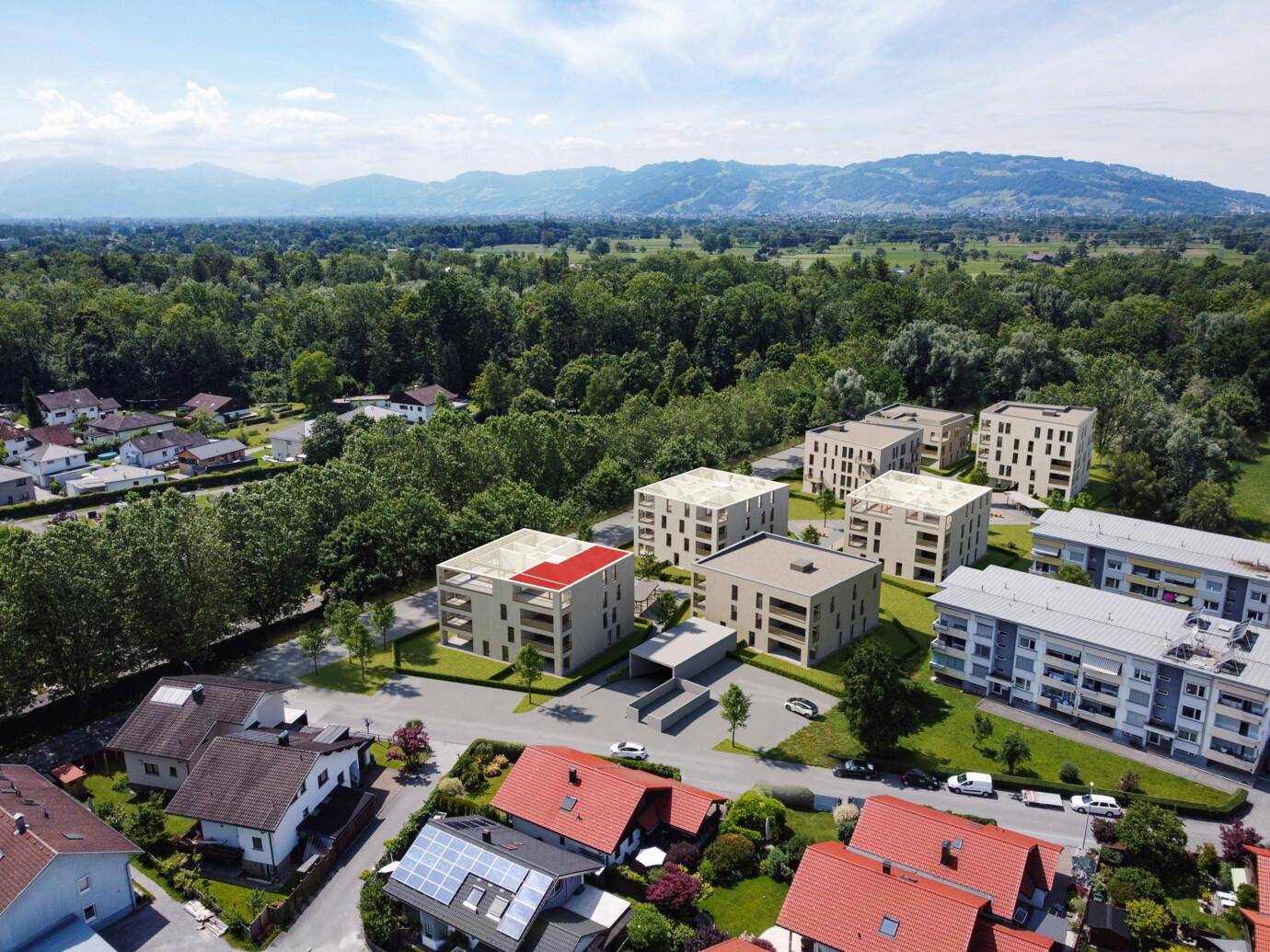 Luftaufnahme eines modernen Wohnkomplexes mit umliegender Natur und Bergblick.