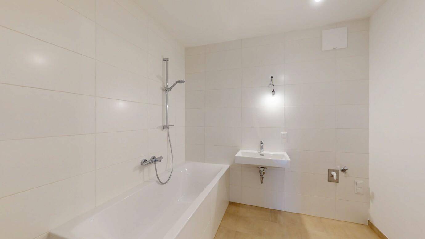 Modernes Badezimmer mit weißen Fliesen, Badewanne und Einzelwaschbecken.
