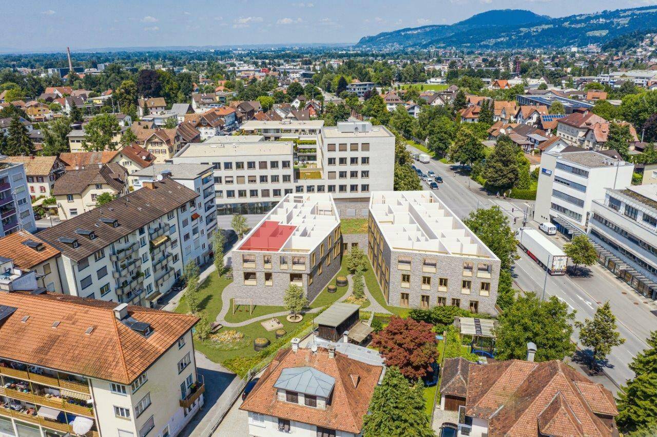 Luftaufnahme eines modernen Wohnkomplexes mit Flachdächern und begrünten Außenbereichen in städtischer Umgebung.