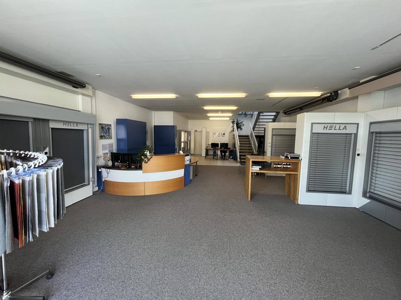 Weitläufiger Büro- und Ausstellungsbereich mit Teppichboden, Empfangsbereich und Produktpräsentationswänden.