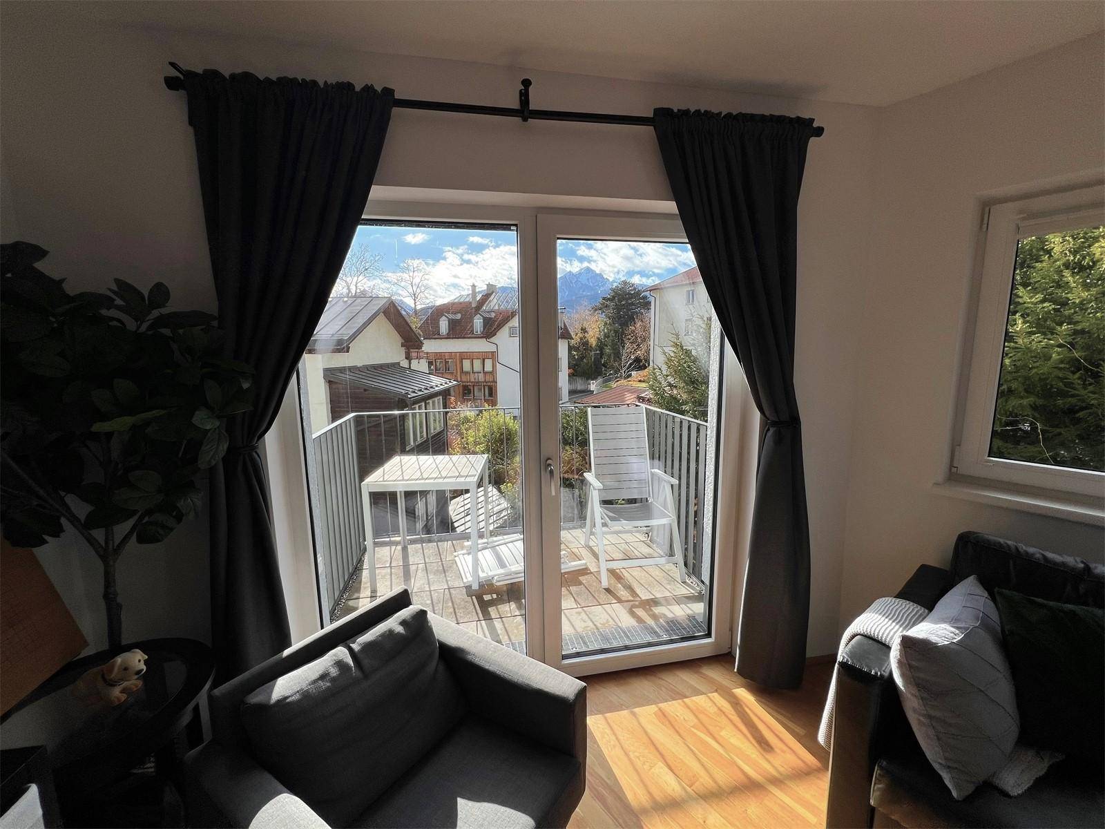Balkonzugang vom Wohnzimmer aus mit Blick auf die umliegenden Häuser und Berge.