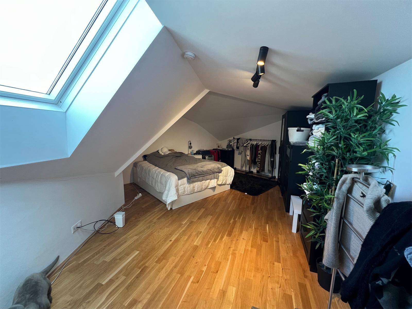 Gemütliches Schlafzimmer im Dachgeschoss mit Holzboden, Dachfenster und Stauraum.