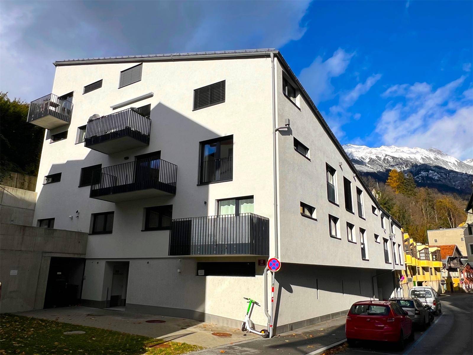 Moderne Gebäudefassade eines Neubaus mit Balkonen und einem beeindruckenden Bergblick.