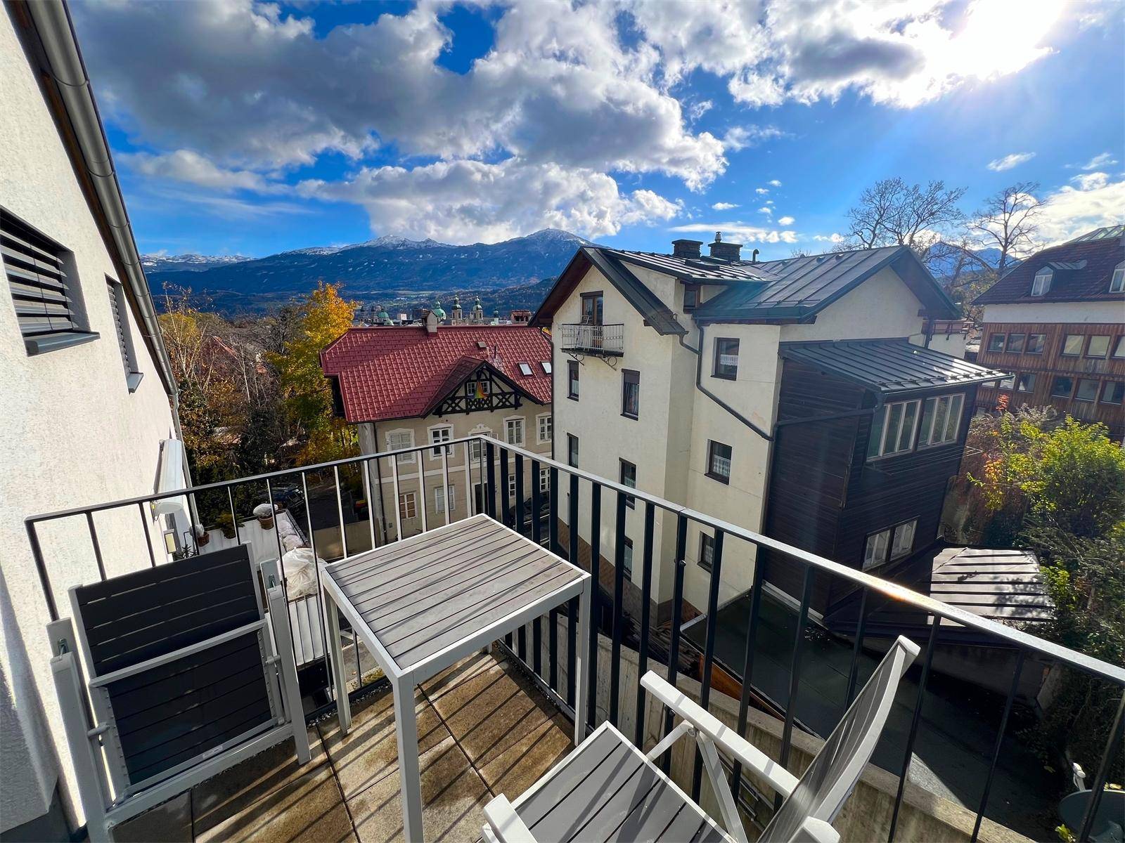 Gemütlicher Balkon mit Sitzgelegenheiten und einem weiten Blick auf die Berge und die Stadt.