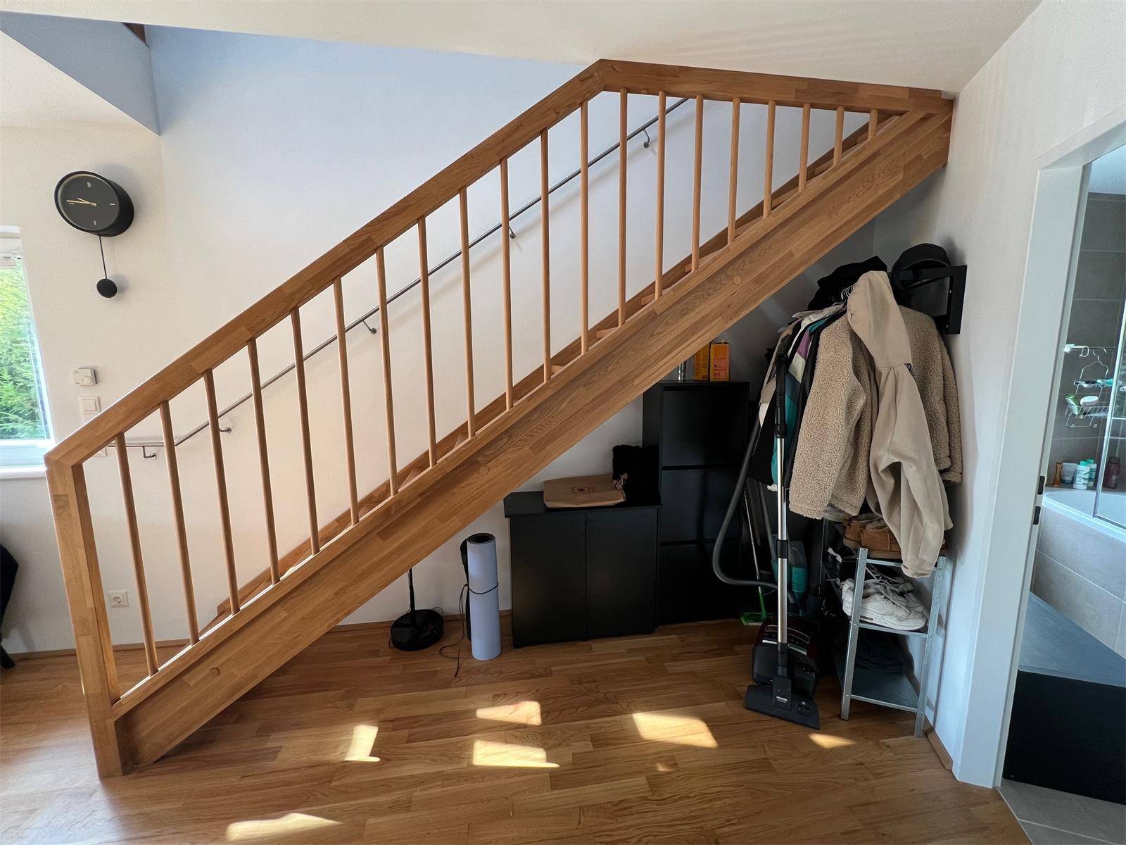 Helle Holztreppe mit Geländer, die die verschiedenen Ebenen der Wohnung verbindet.