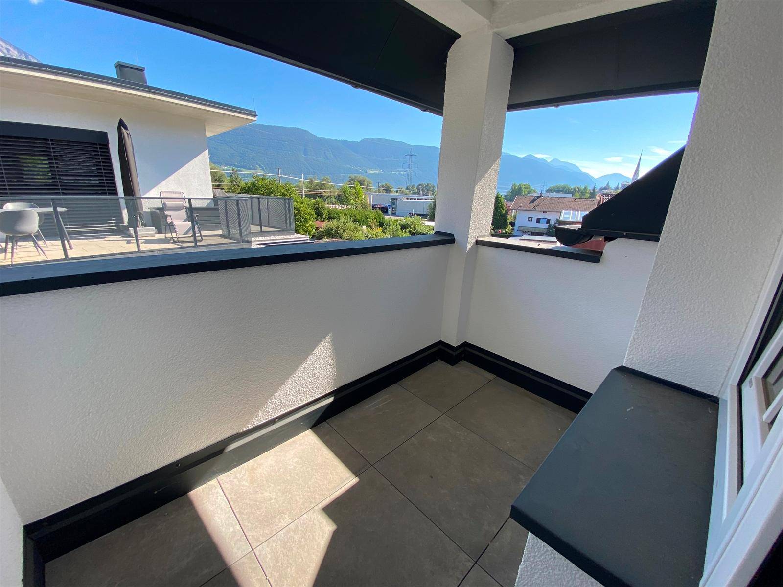 Kleiner Balkon mit Fliesenboden und weitem Blick auf die Berge und die grüne Umgebung.