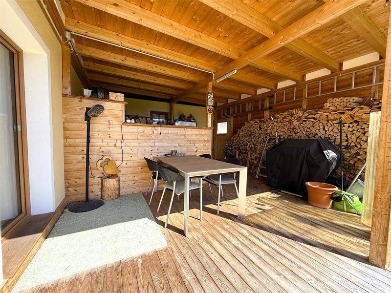 Überdachte Holzterrasse mit Esstisch und Stühlen, ideal für Mahlzeiten im Freien.