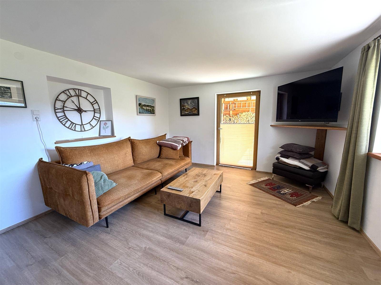 Helles Wohnzimmer mit bequemem braunem Sofa, Holztisch und dekorativer Wanduhr.