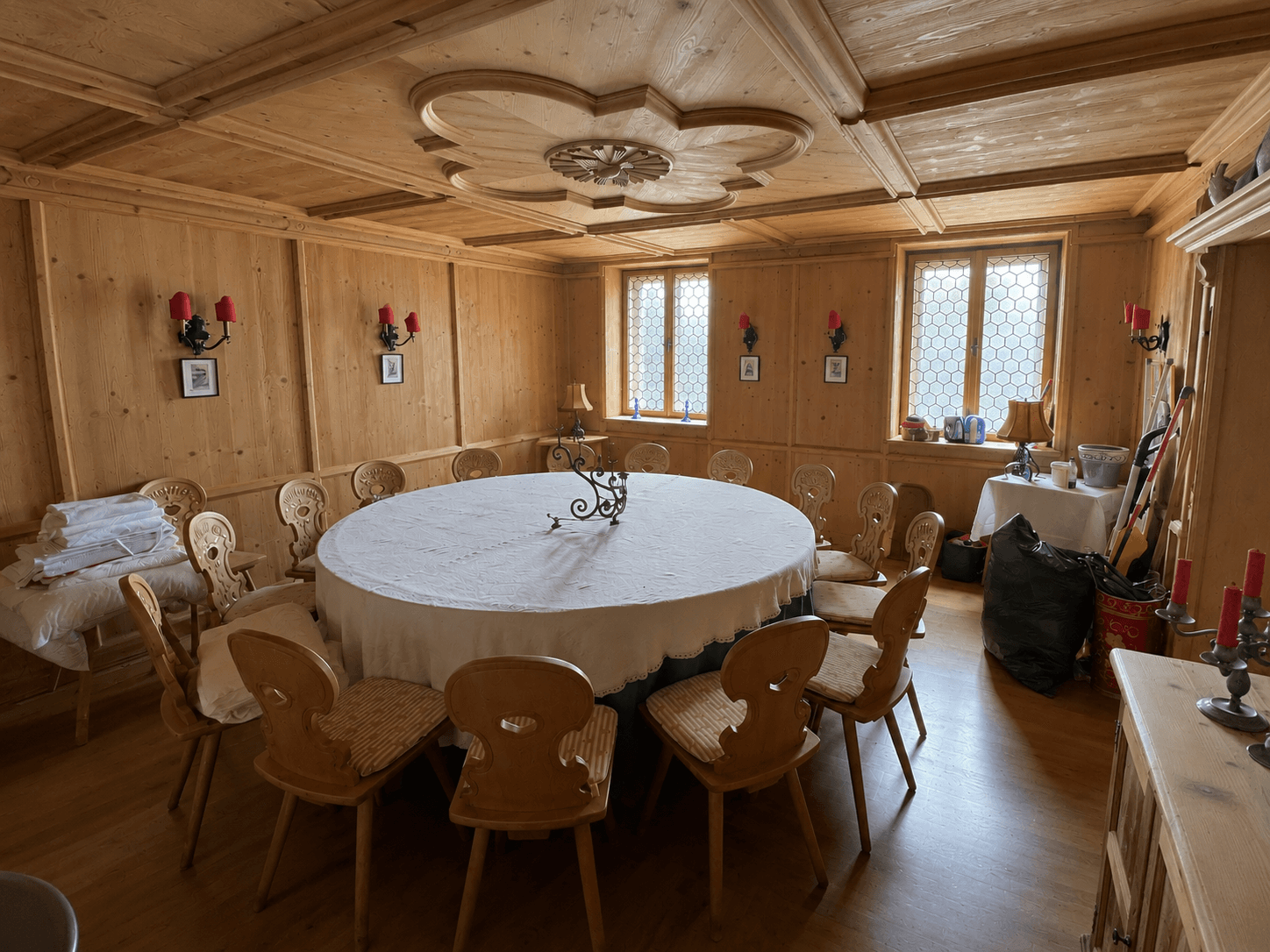 Gemütlicher Speisesaal mit Holzvertäfelung, runden Tischen und traditionellen Stühlen.