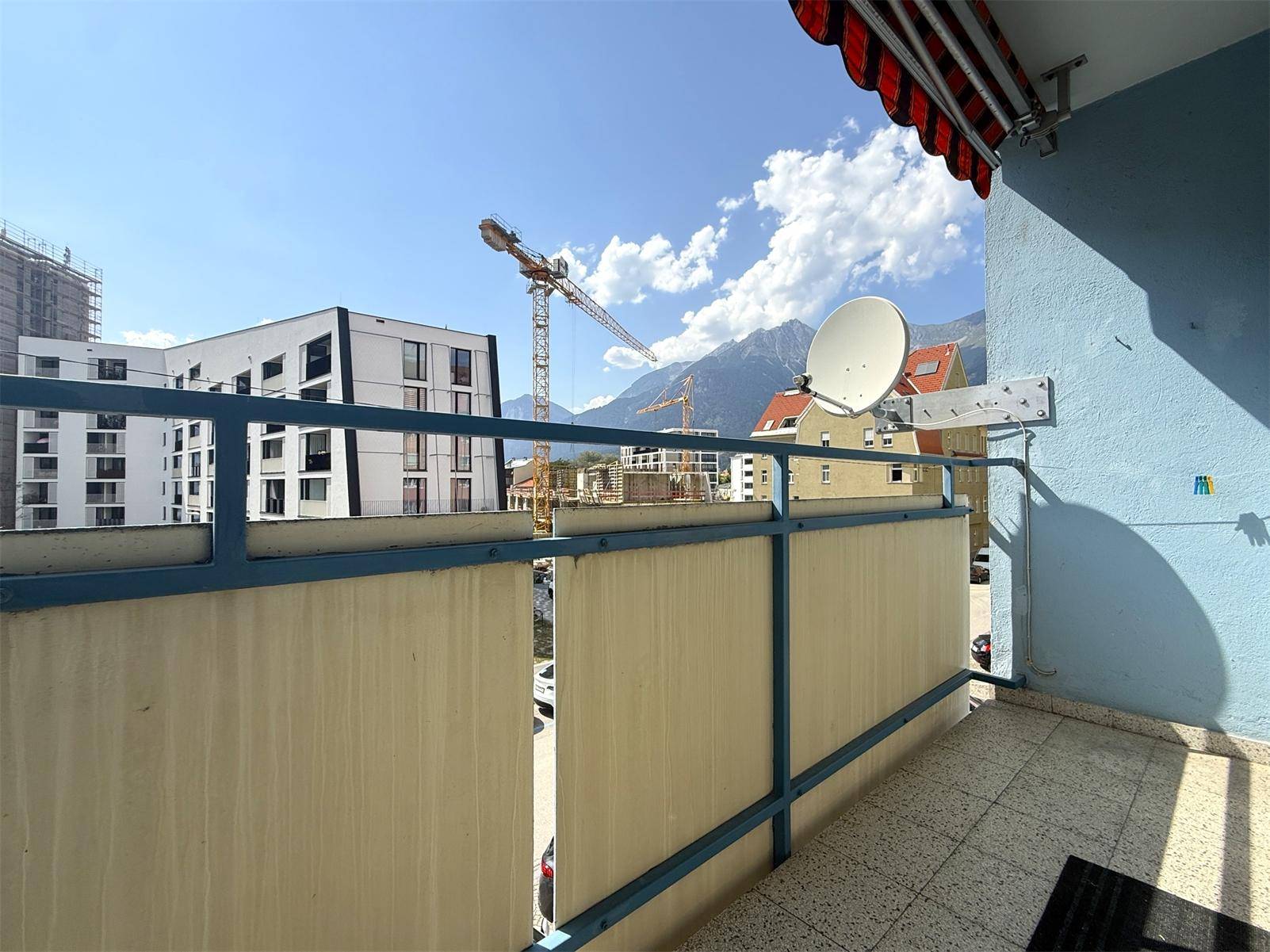 Balkon mit Blick auf Baustellenkräne, umliegende Gebäude und die majestätischen Berge.