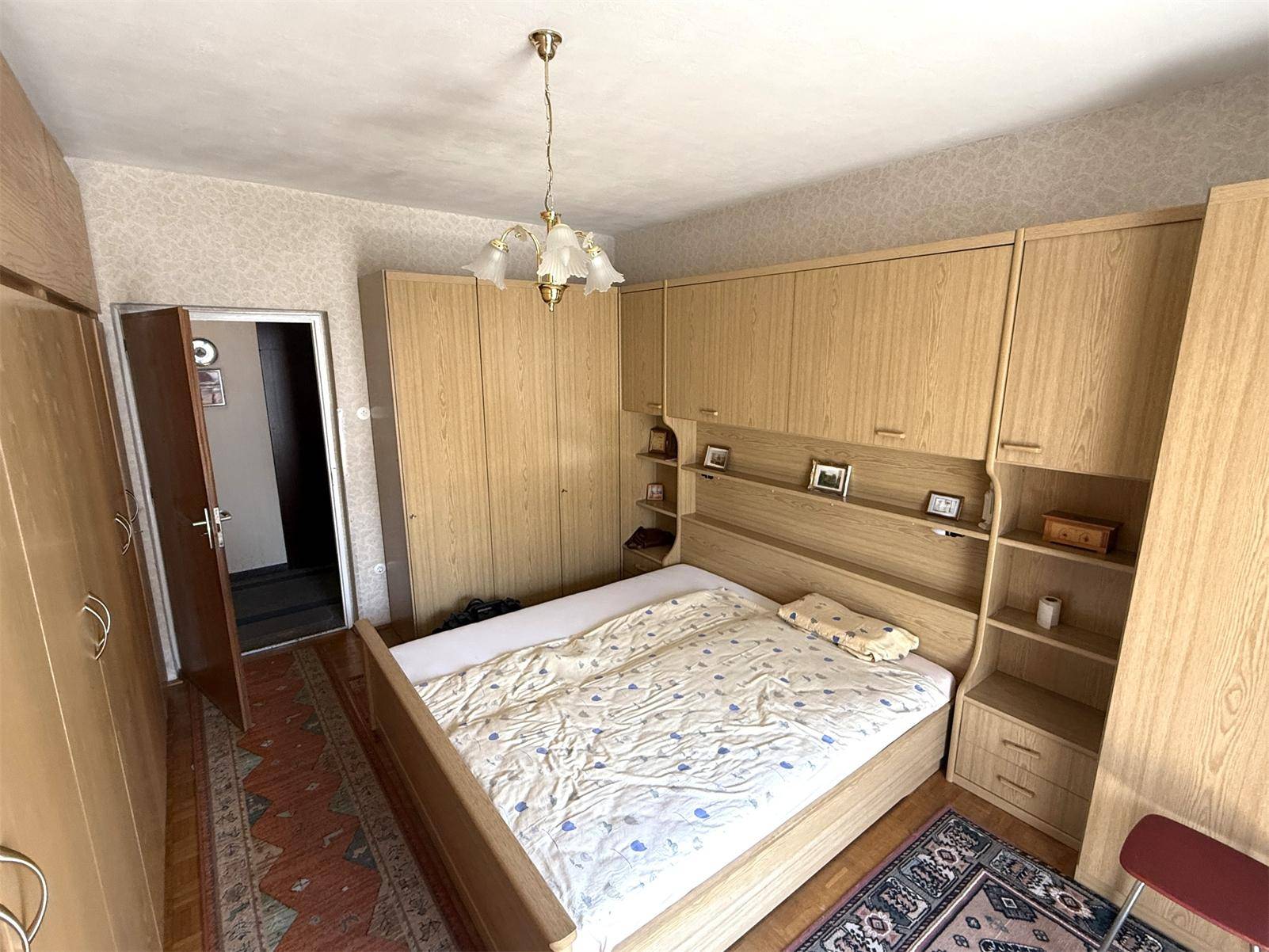 Schlafzimmer mit großem Bett, integrierten Holzschränken und einem traditionellen Teppich auf dem Boden.