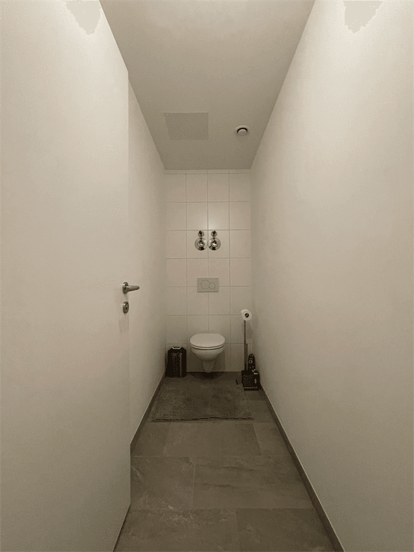 Separates WC mit Toilette und Fliesenboden in einem schmalen, funktionalen Raum.