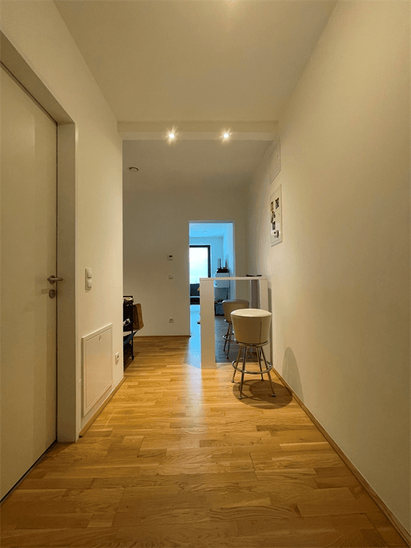 Langer, heller Flur mit Parkettboden und Zugang zu weiteren Räumen der Wohnung.