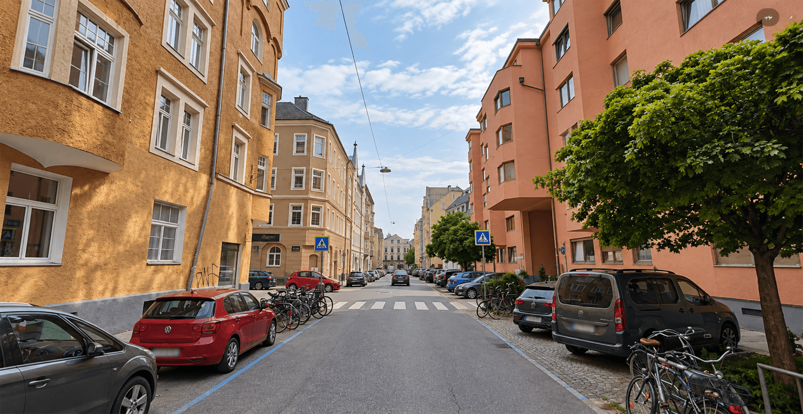 Städtische Straße mit historischen und modernen Gebäuden, vielen parkenden Autos und Fahrrädern.