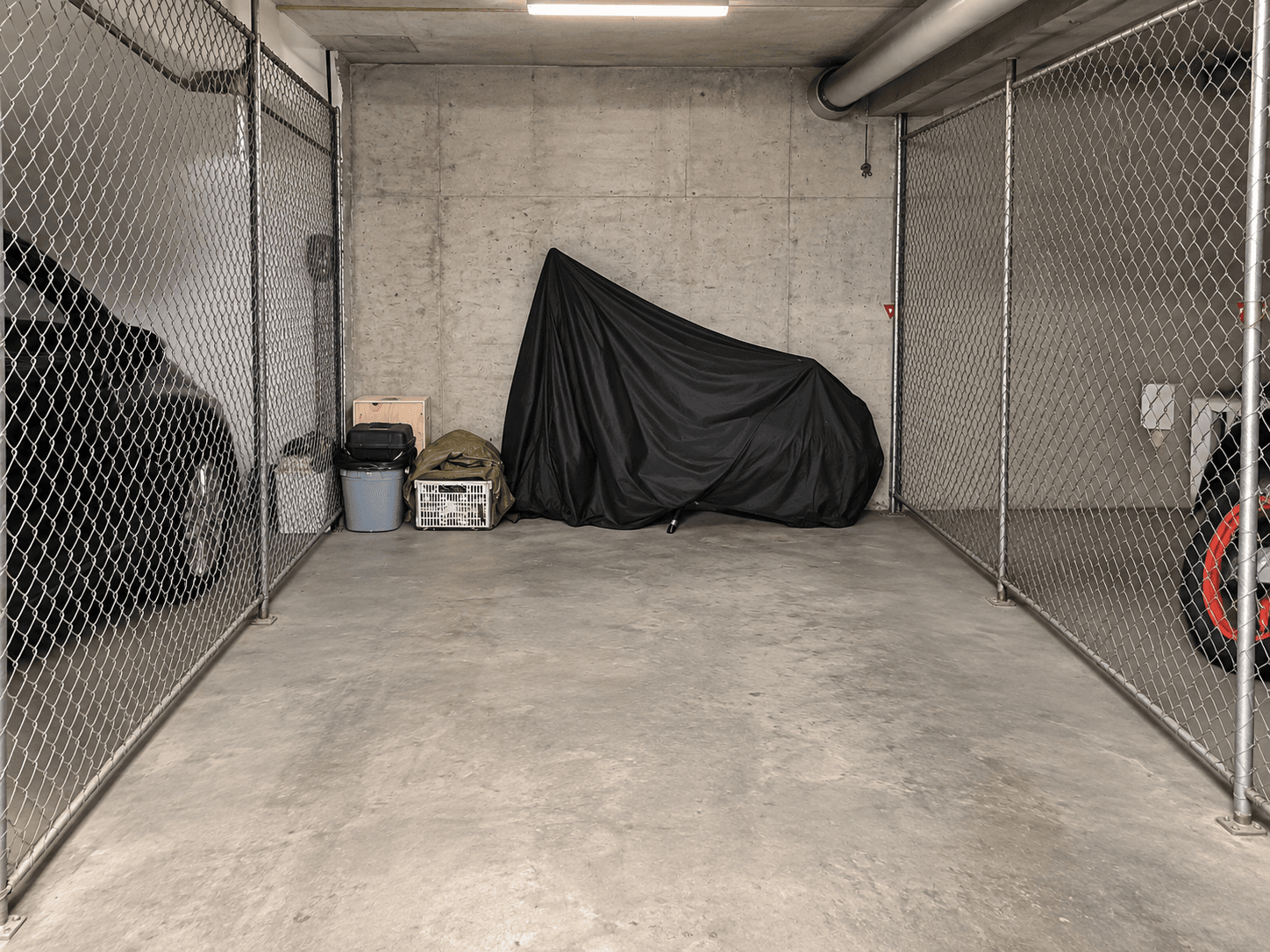 Abgetrennter Lagerbereich in einer Tiefgarage mit Betonwänden und Drahtzaun.