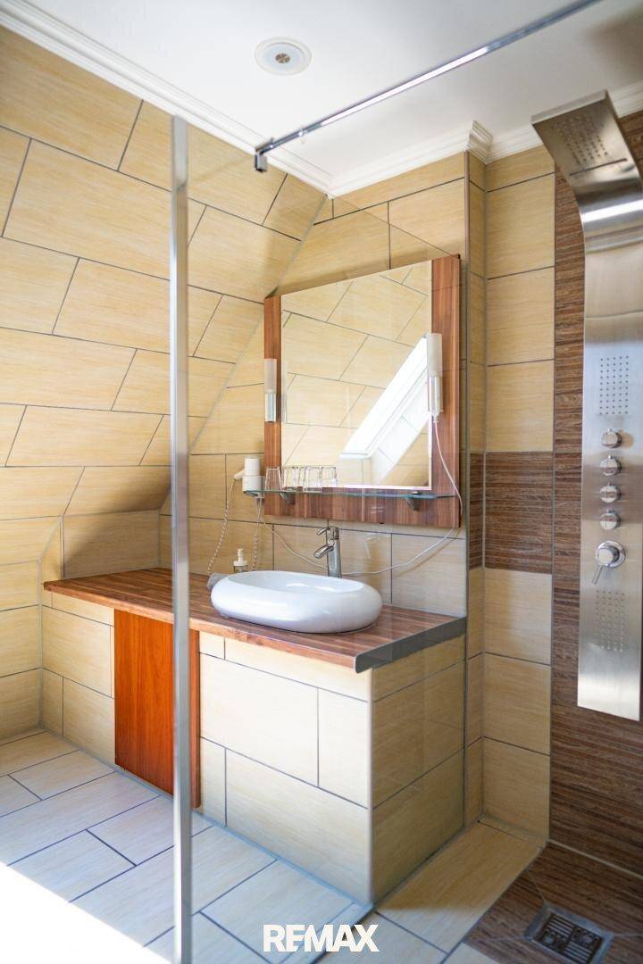 Modernes Badezimmer mit Waschtisch, Aufsatzwaschbecken, Spiegel und begehbarer Dusche.