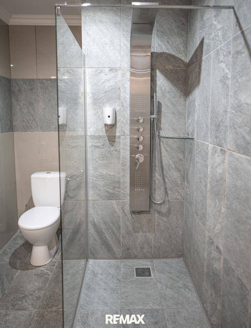 Modernes Badezimmer mit begehbarer Dusche, grauen Fliesen und Toilette, funktional und stilvoll.