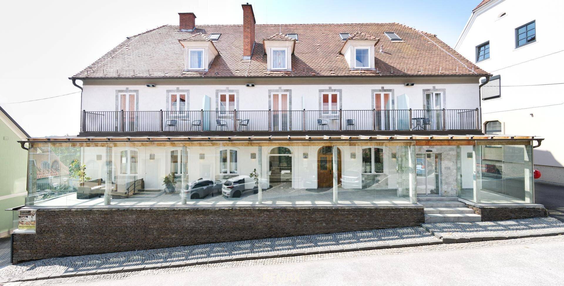 Die moderne Fassade des Gebäudes mit Balkonen und einer verglasten Erdgeschosszone.
