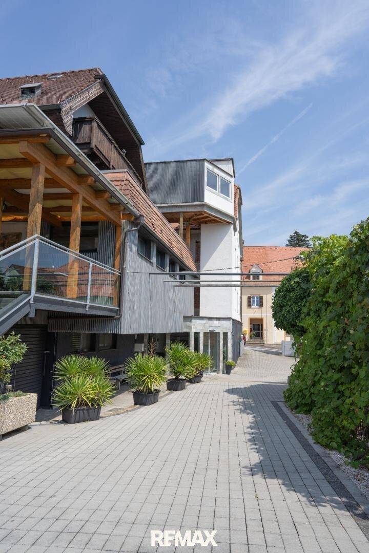 Eingangsbereich eines Gebäudes mit moderner Architektur, gepflastertem Weg und einer barrierefreien Rampe.