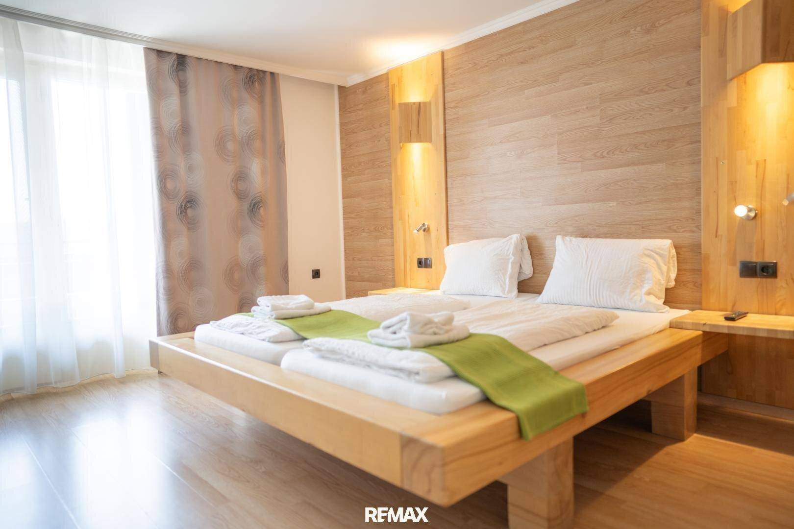 Helles Schlafzimmer mit Holzbettrahmen, Holzvertäfelung und hellem Boden, einladend und modern.