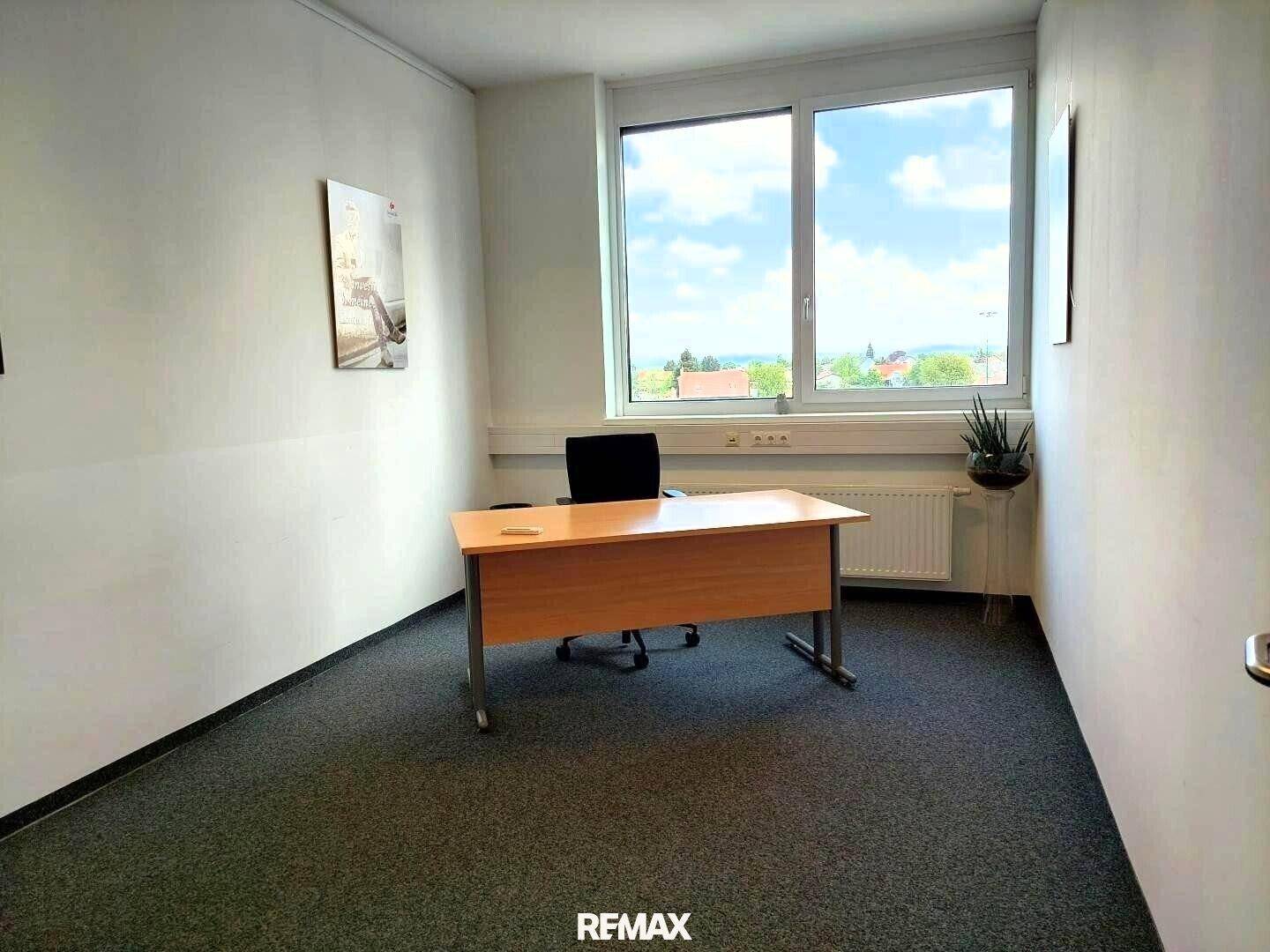 Helles Einzelbüro mit Schreibtisch und Bürostuhl, großen Fenstern und weitem Blick über die Landschaft.