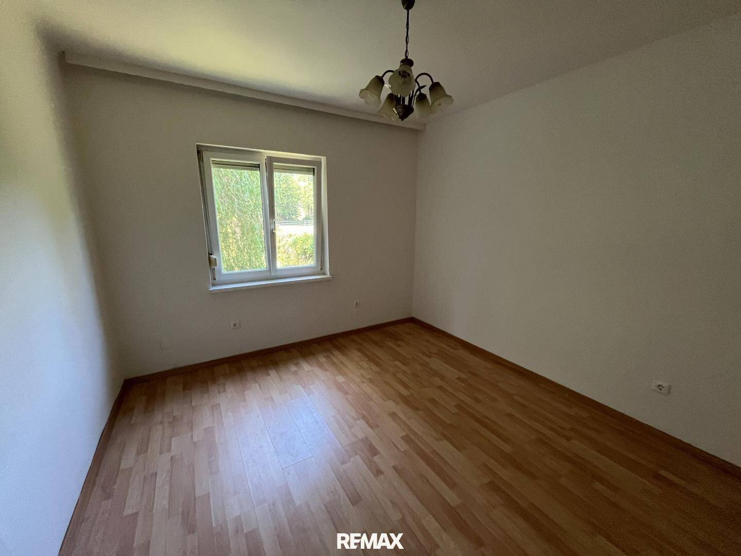 Gemütliches Schlafzimmer mit Laminatboden und Fenster, ideal für ein Kinder- oder Gästezimmer.