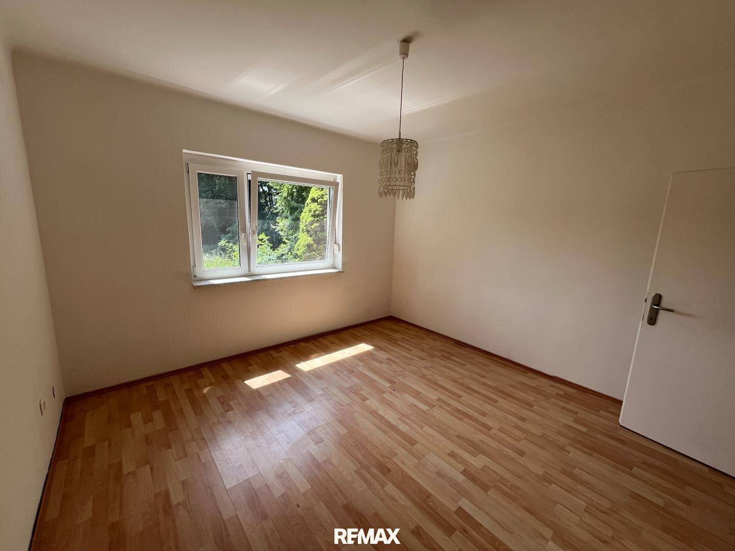 Geräumiges Schlafzimmer mit Laminatboden und viel Tageslicht durch das große Fenster.