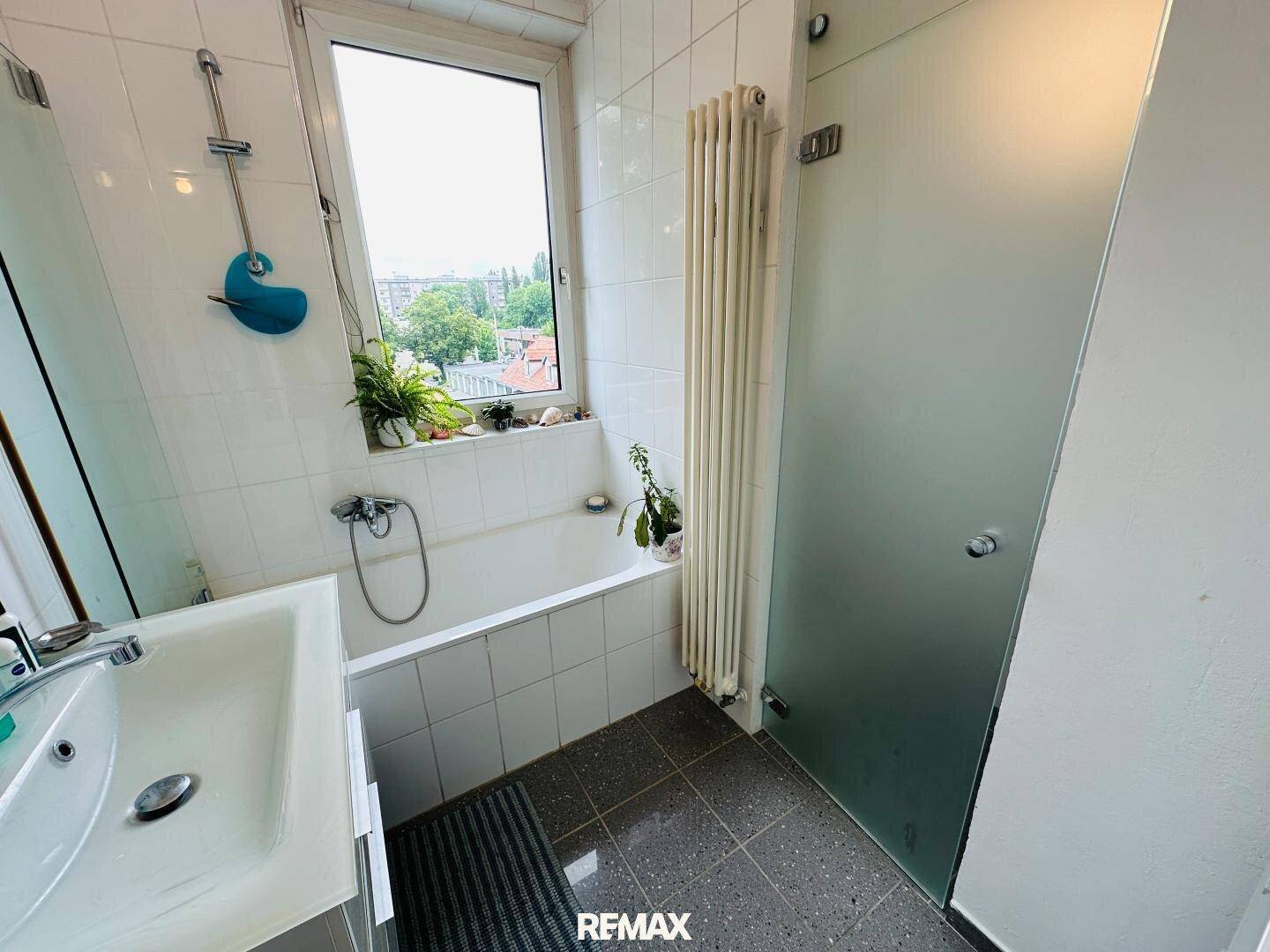 Badezimmer mit Badewanne, Waschbecken und Fenster für Tageslicht.