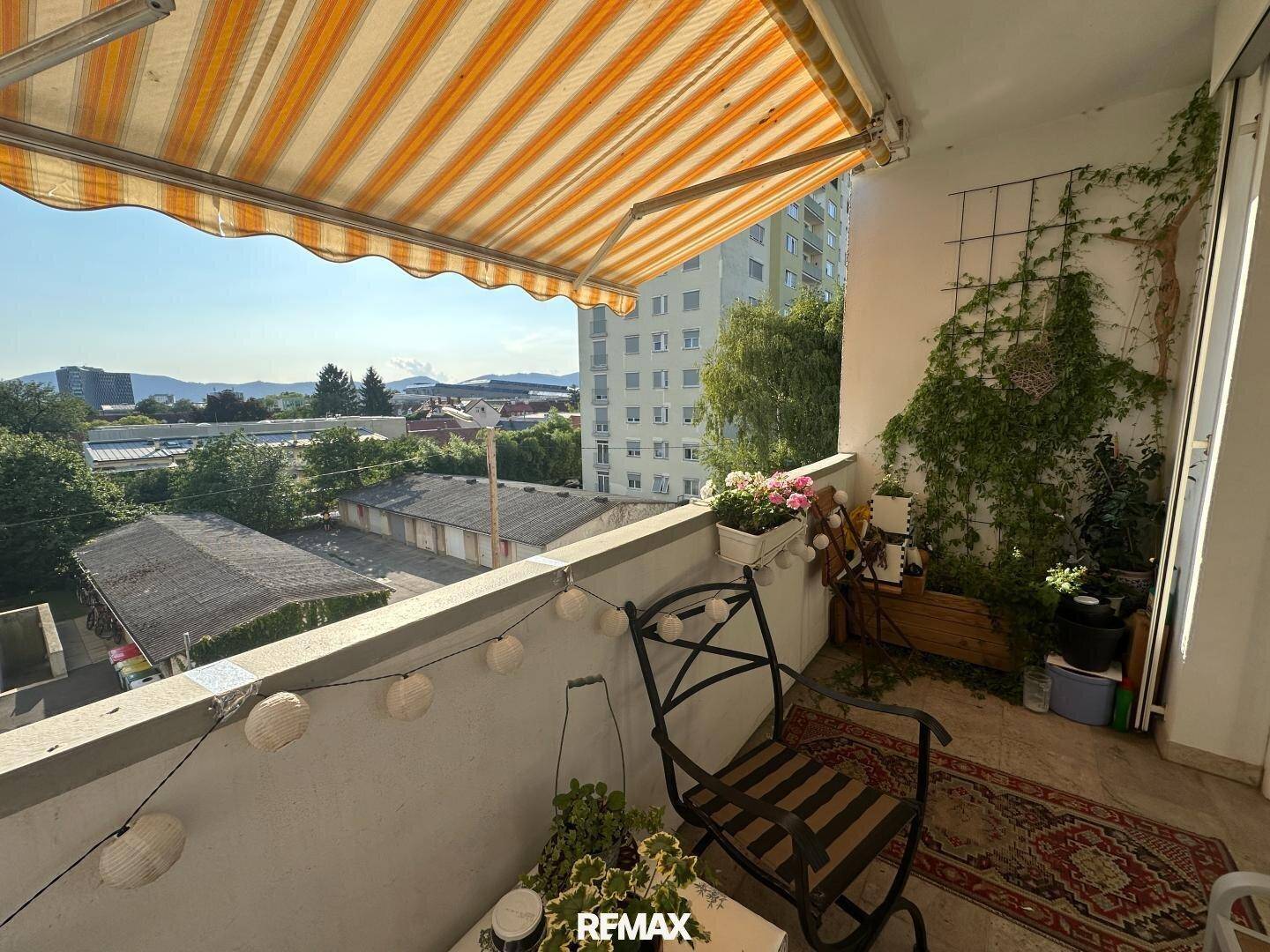 Sonniger Balkon mit Markise, Sitzgelegenheiten und Blick auf die Umgebung.