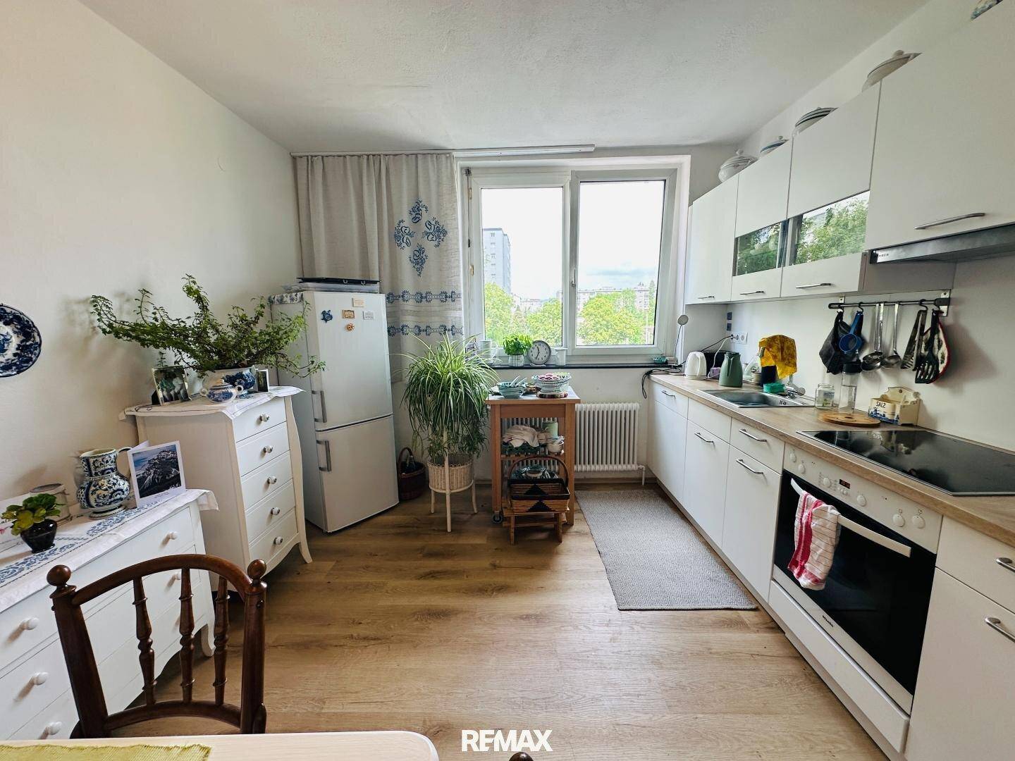 Helle Küche mit weißen Schränken, modernen Geräten und Fenster.
